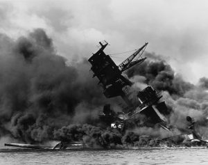 The USS Arizona (BB-39) burning after the Japanese attack on Pearl Harbor, 7 December 1941. USS Arizona sunk at Pearl Harbor. The ship is resting on the harbor bottom. The supporting structure of the forward tripod mast has collapsed after the forward magazine exploded.