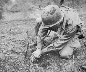 An American infantryman probes for landmines using a knife.