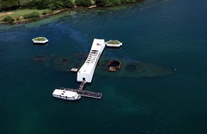 An aerial view of the USS Arizona Memorial with a US Navy (USN) Tour Boat, USS Arizona Memorial Detachment, moored at the pier as visitor disembark to visit and pay their respects to the Sailors and Marines who lost their lives during the attack on Pearl Harbor on December 7, 1941. (Released to Public) Location: PEARL HARBOR, HAWAII (HI) UNITED STATES OF AMERICA (USA) DoD photo by: PH3(AW/SW) JAYME PASTORIC, USN
